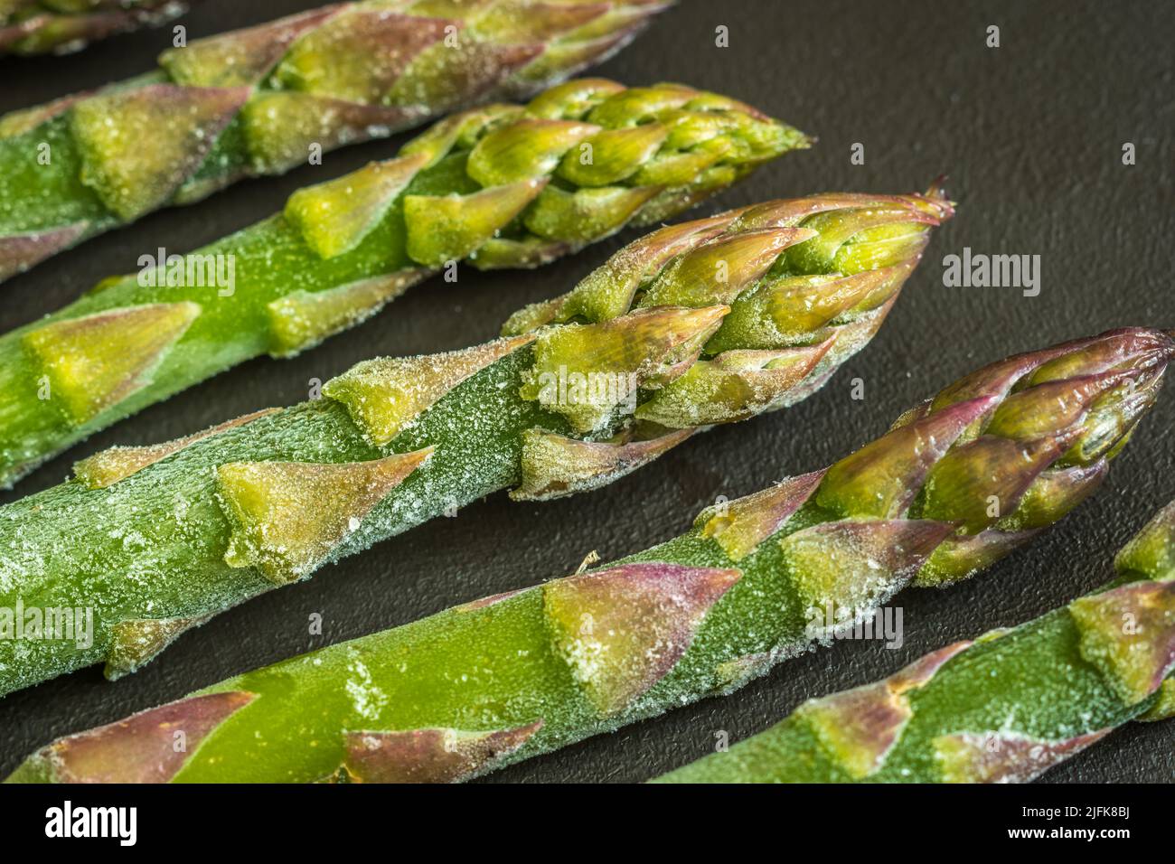Gambi di asparagi congelati su sfondo scuro primo piano Foto Stock