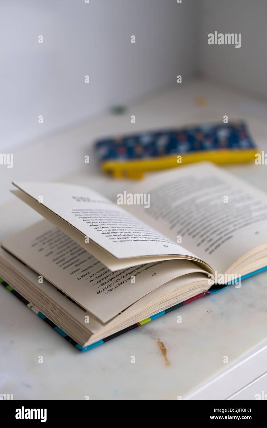 Una vista verticale di uno storybook aperto e di una custodia a matita sul tavolo bianco Foto Stock