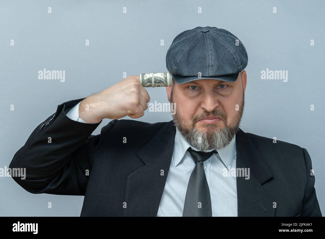 L'uomo mise il dito sul suo tempio. Il dito è avvolto in una fattura del dollaro. Sembra che voglia sparare a se stesso. Foto Stock