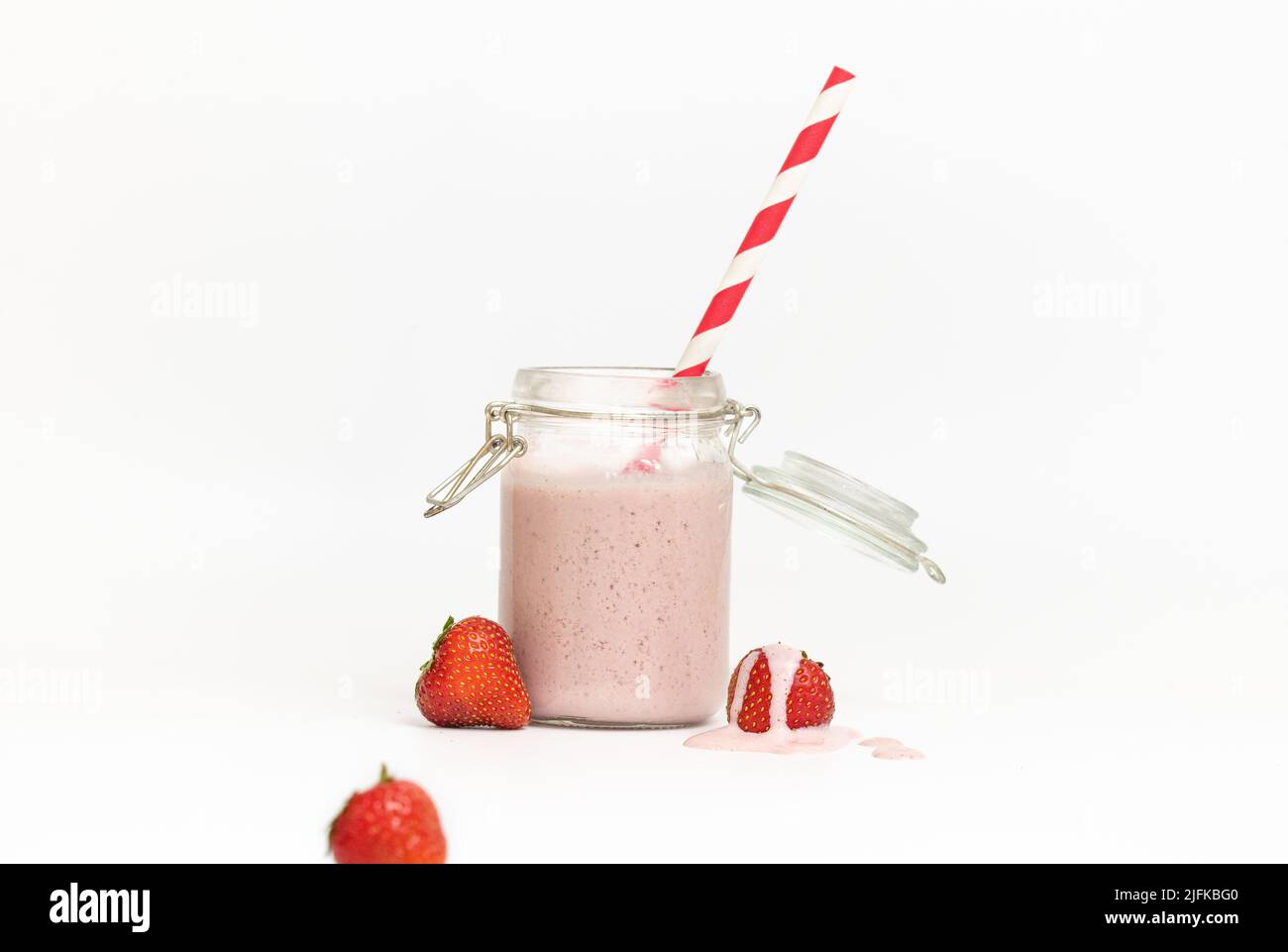 Foto studio di un frullato o fragola con paglia rossa su sfondo bianco Foto Stock
