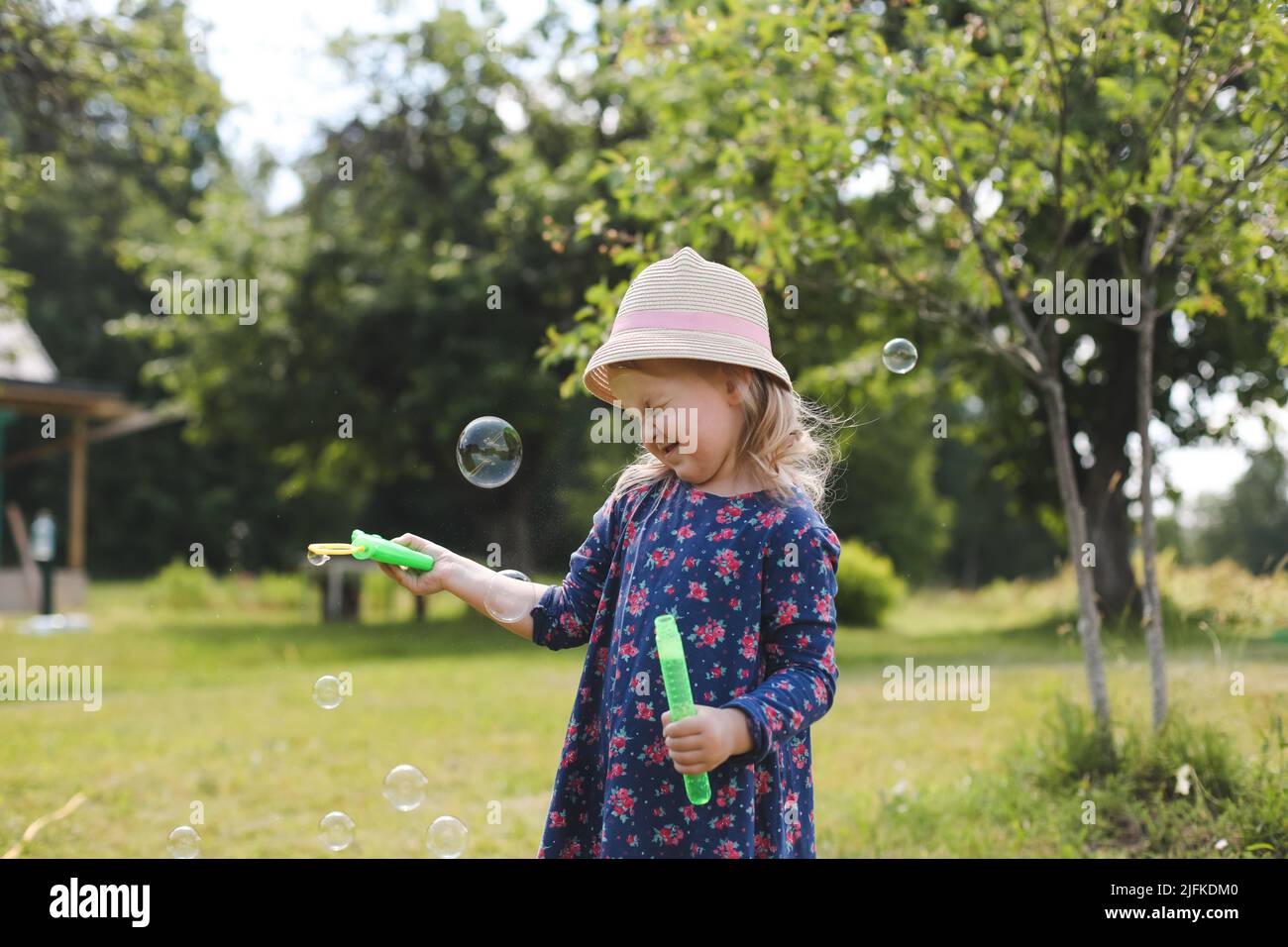 Carino ragazza piccola che soffia le bolle di sapone su una passeggiata in estate all'aperto Foto Stock