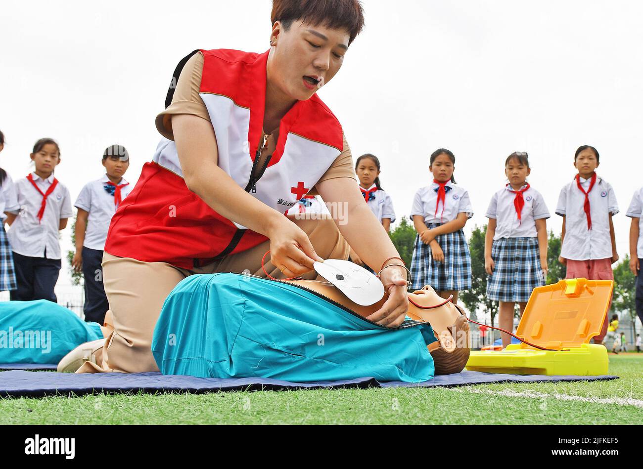 YANTAI, CINA - 4 LUGLIO 2022 - i volontari della Croce Rossa insegnano agli studenti come usare il defibrillatore automatico esterno alla Scuola primaria di Menlou Touyu Foto Stock