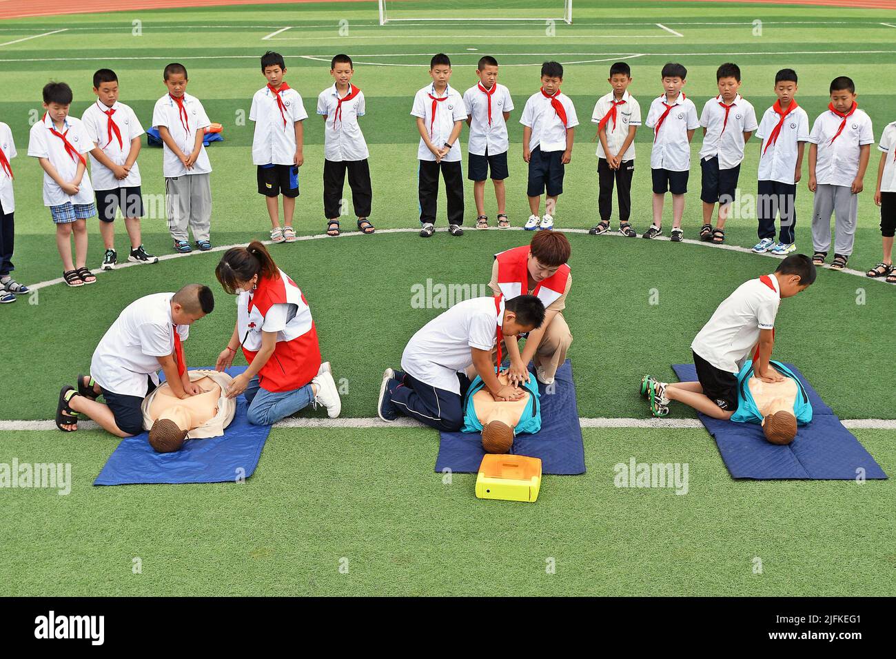 YANTAI, CINA - 4 LUGLIO 2022 - gli studenti delle scuole elementari praticano le abilità di pronto soccorso RCP sotto la guida di volontari della Croce Rossa, Yantai City, Shandong Foto Stock