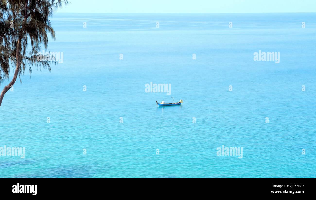 Da solo piccola barca su una superficie di mare blu pulito. Tradizionale barca di legno tailandese vela in mare aperto calmo in caldo giorno d'estate. Paesaggio tropicale luminoso, esotico Foto Stock