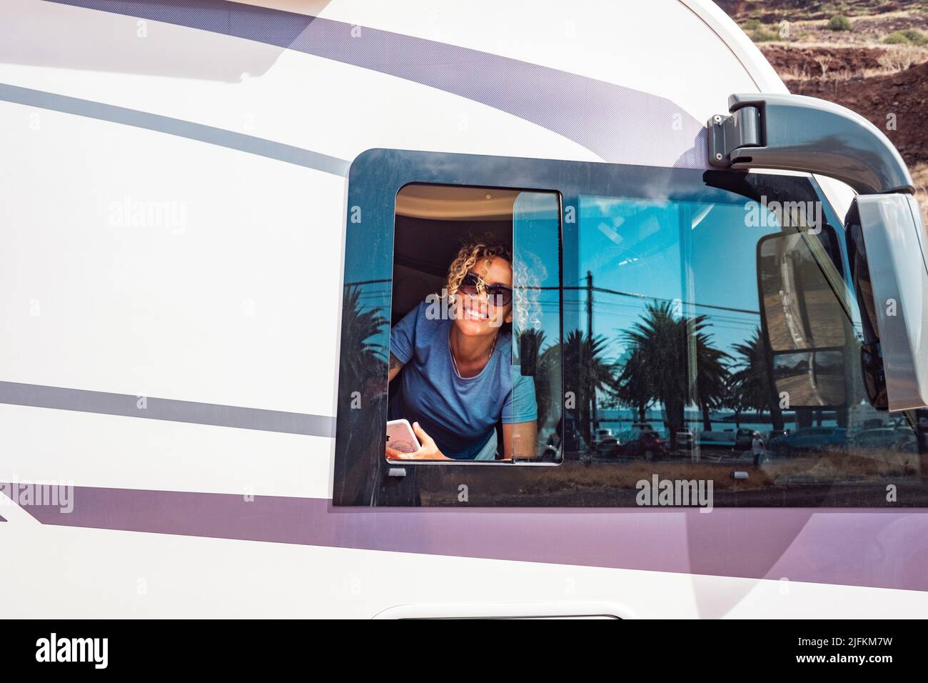 Felice ritratto donna sorridente alla finestra del suo moderno camper van motor home. Concetto di turista e di viaggio per vacanza o vita furgone Foto Stock