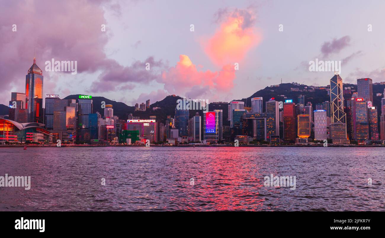 Hong Kong - 13 luglio 2017: Quartiere Centrale di Hong Kong in serata, grattacieli illuminati si erigono lungo la costa, moderno paesaggio urbano asiatico Foto Stock
