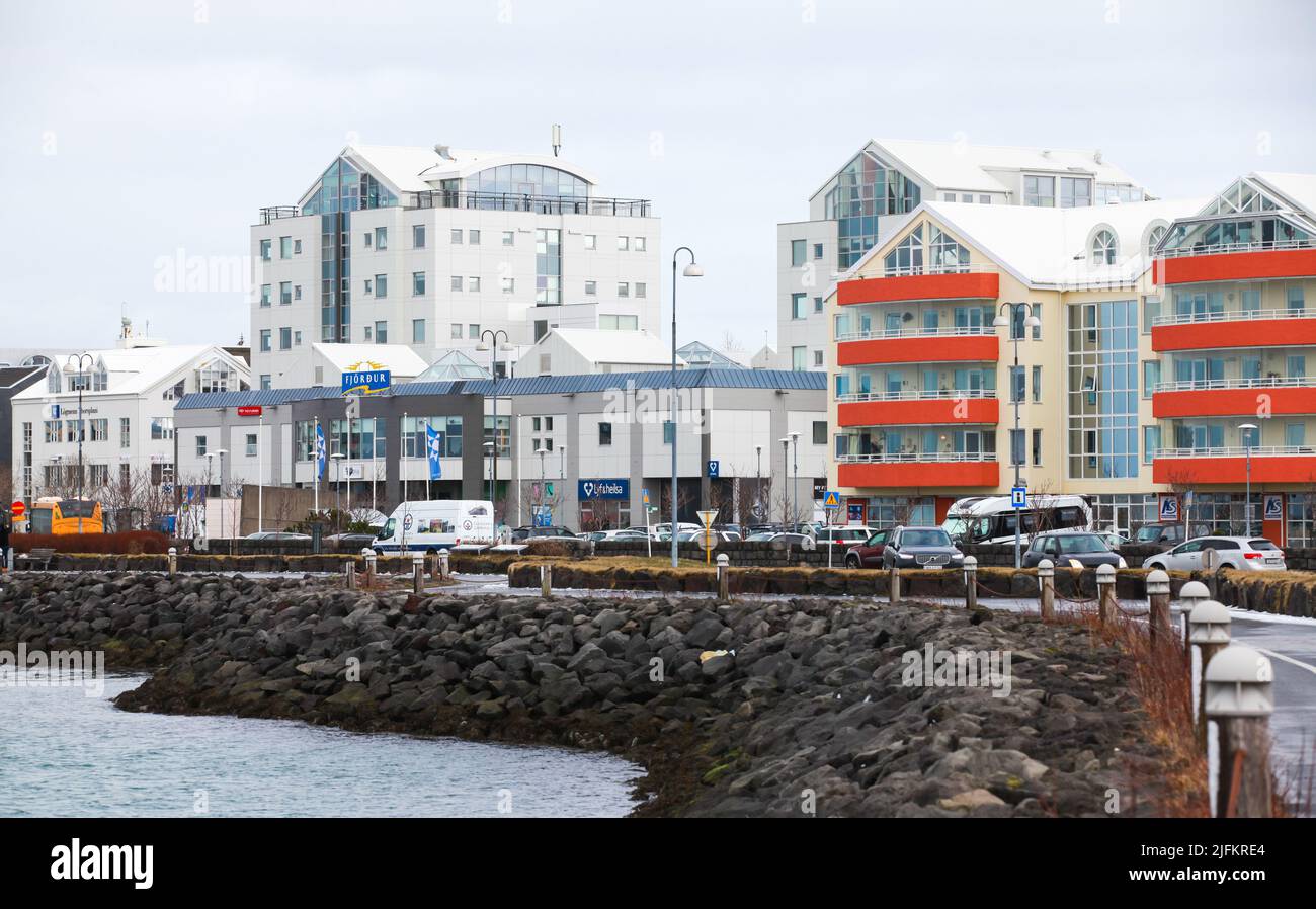 Hafnarfjordur, Islanda - 4 aprile 2017: Hafnarfjordur paesaggio costiero con moderne case residenziali di giorno, gente comune e automobili sono su t Foto Stock