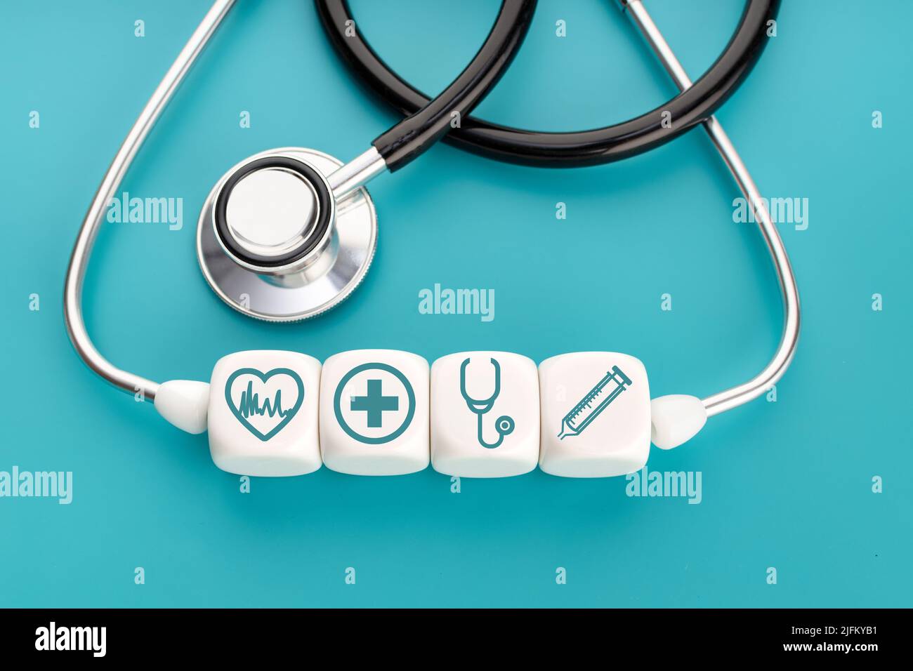 Concetto di assistenza sanitaria o medicina. Simbolo medico sanitario su blocchi bianchi e stetoscopio su sfondo verde Foto Stock
