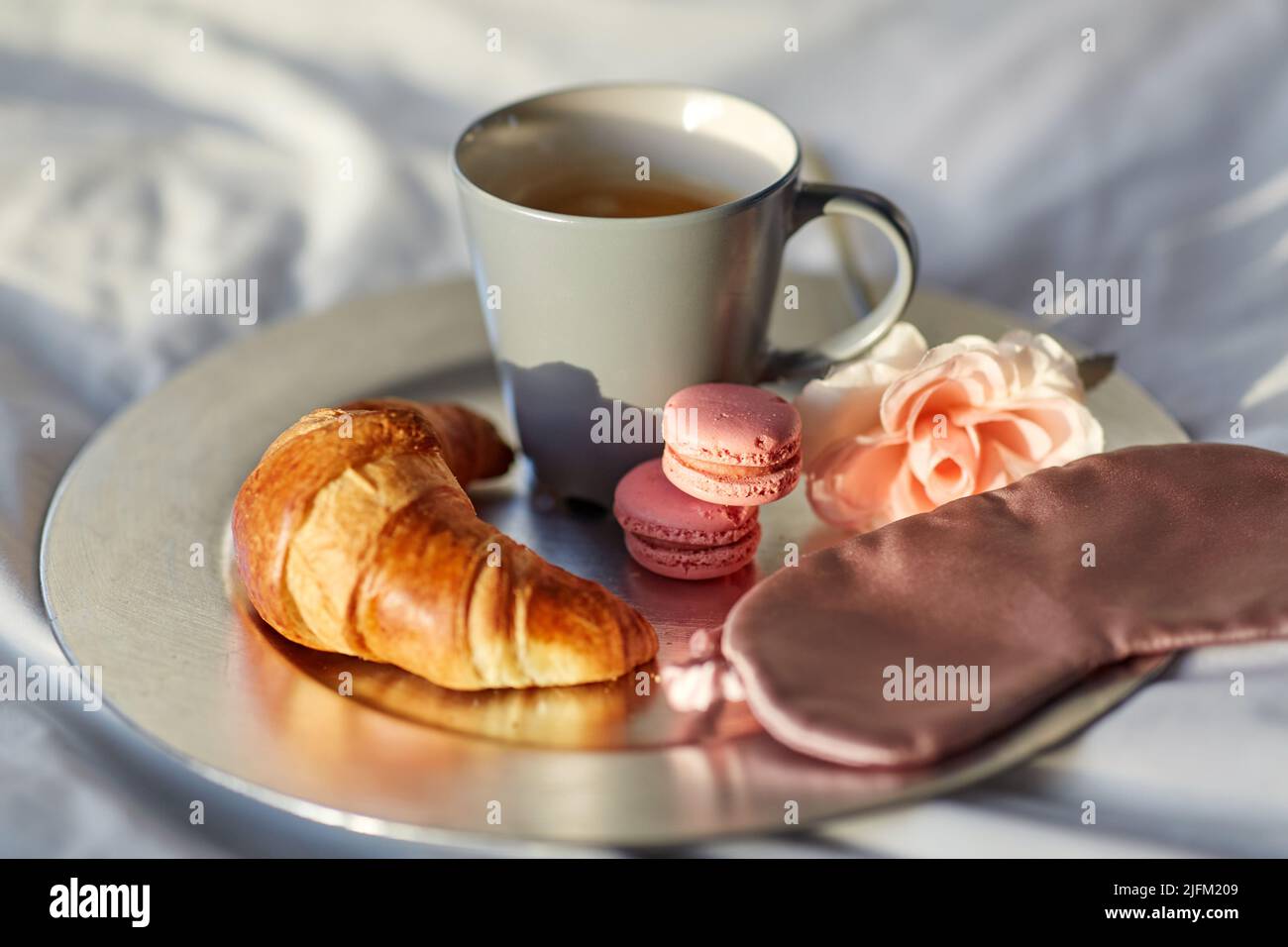 croissant, caffè e maschera per gli occhi a letto Foto Stock