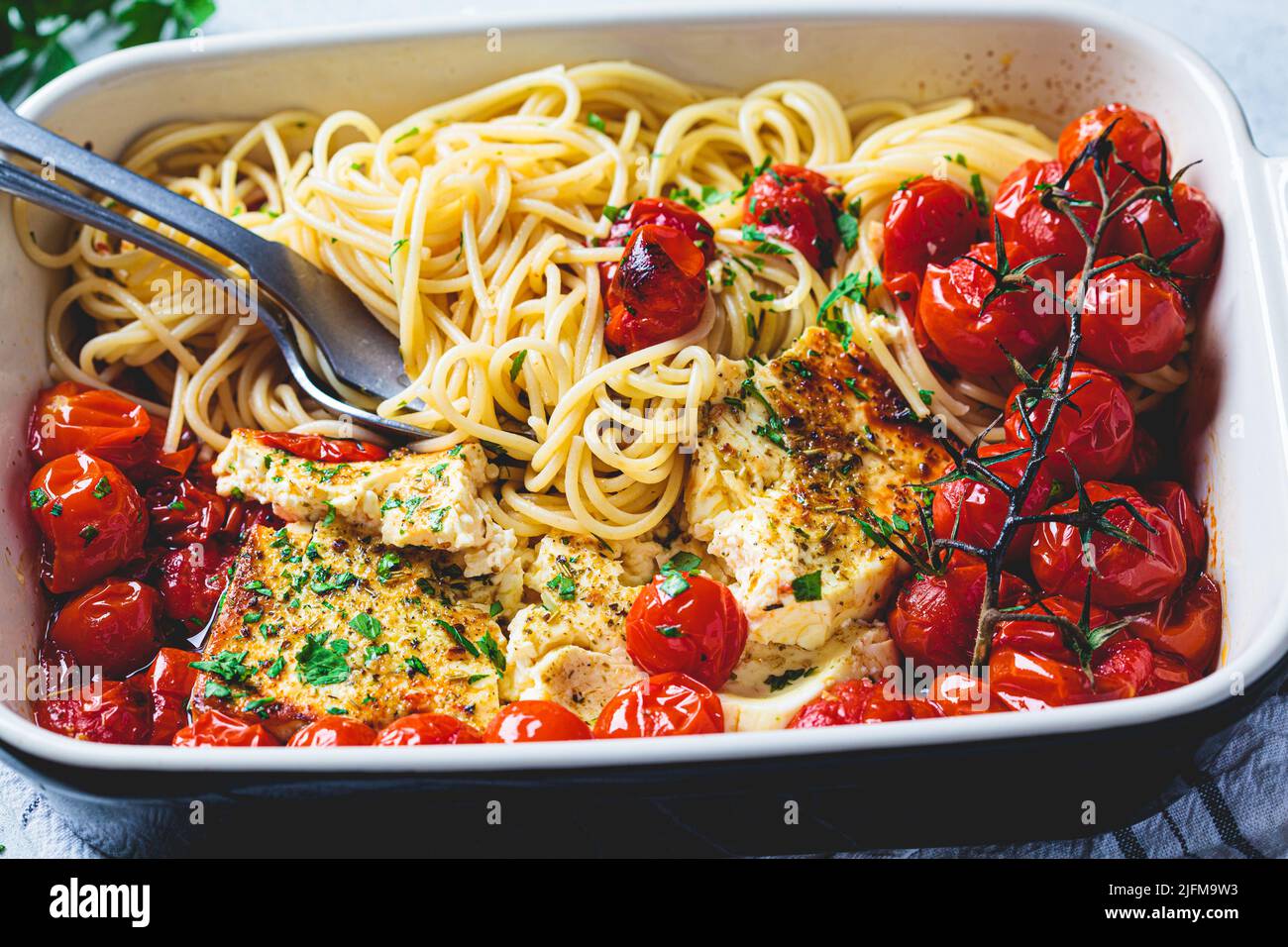 Feta al forno con pomodoro e spaghetti in un piatto. Ricetta casereccia alla moda. Foto Stock