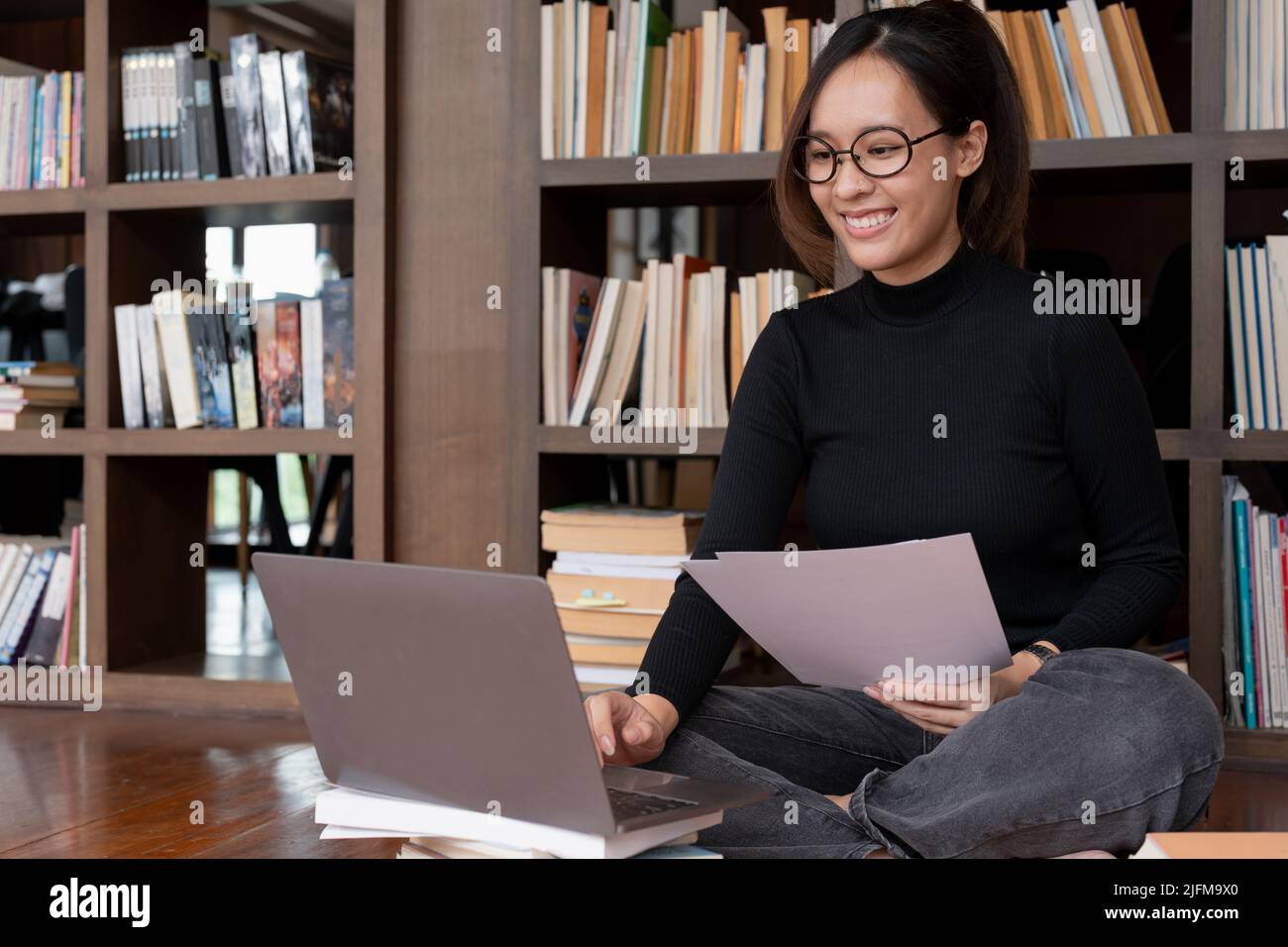 Biblioteca universitaria: Bella donna asiatica usa il laptop, studiare per l'assegnazione di classe. Studenti focalizzati imparare, studiare per esami universitari. Foto Stock