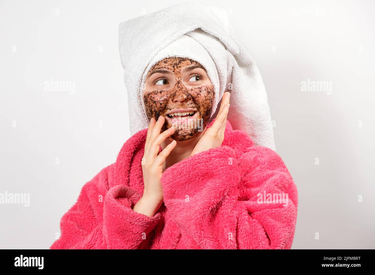 Una donna fa una macchia facciale da chicchi di caffè e guarda via, copiando lo spazio per il testo Foto Stock