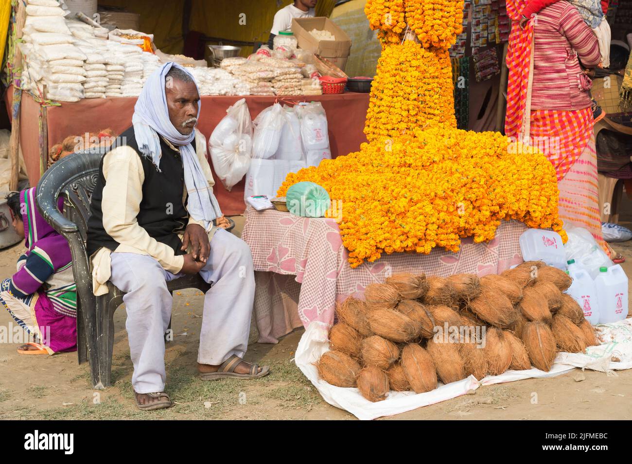 L’uomo indiano che vende noci di cocco e ghirlande di fiori di Marigold, Allahabad Kumbh Mela, il più grande raduno religioso del mondo, Uttar Pradesh, India Foto Stock