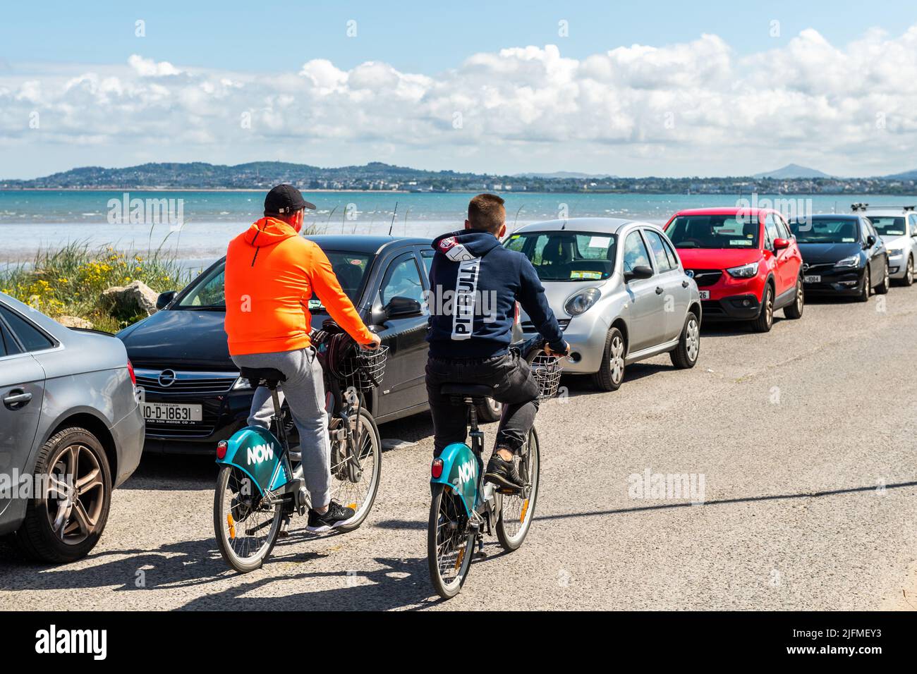 Due uomini a noleggio biciclette in una giornata di sole al porto di Dublino, Dublino, Irlanda. Foto Stock