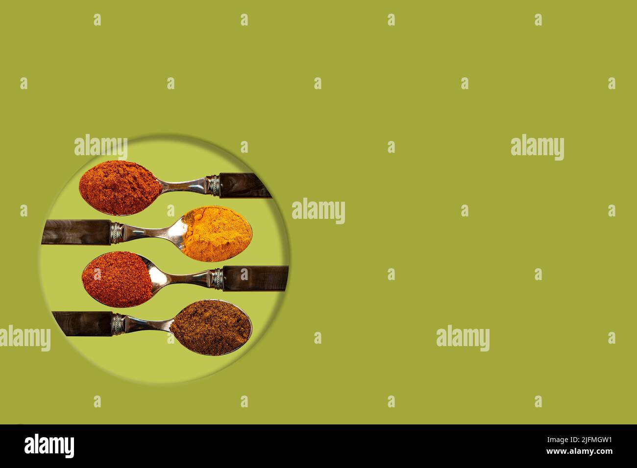 Una selezione di spezie in polvere di curry di peperoncino cayenne, utilizzate nella cucina indiana su un colorato sfondo verde Foto Stock