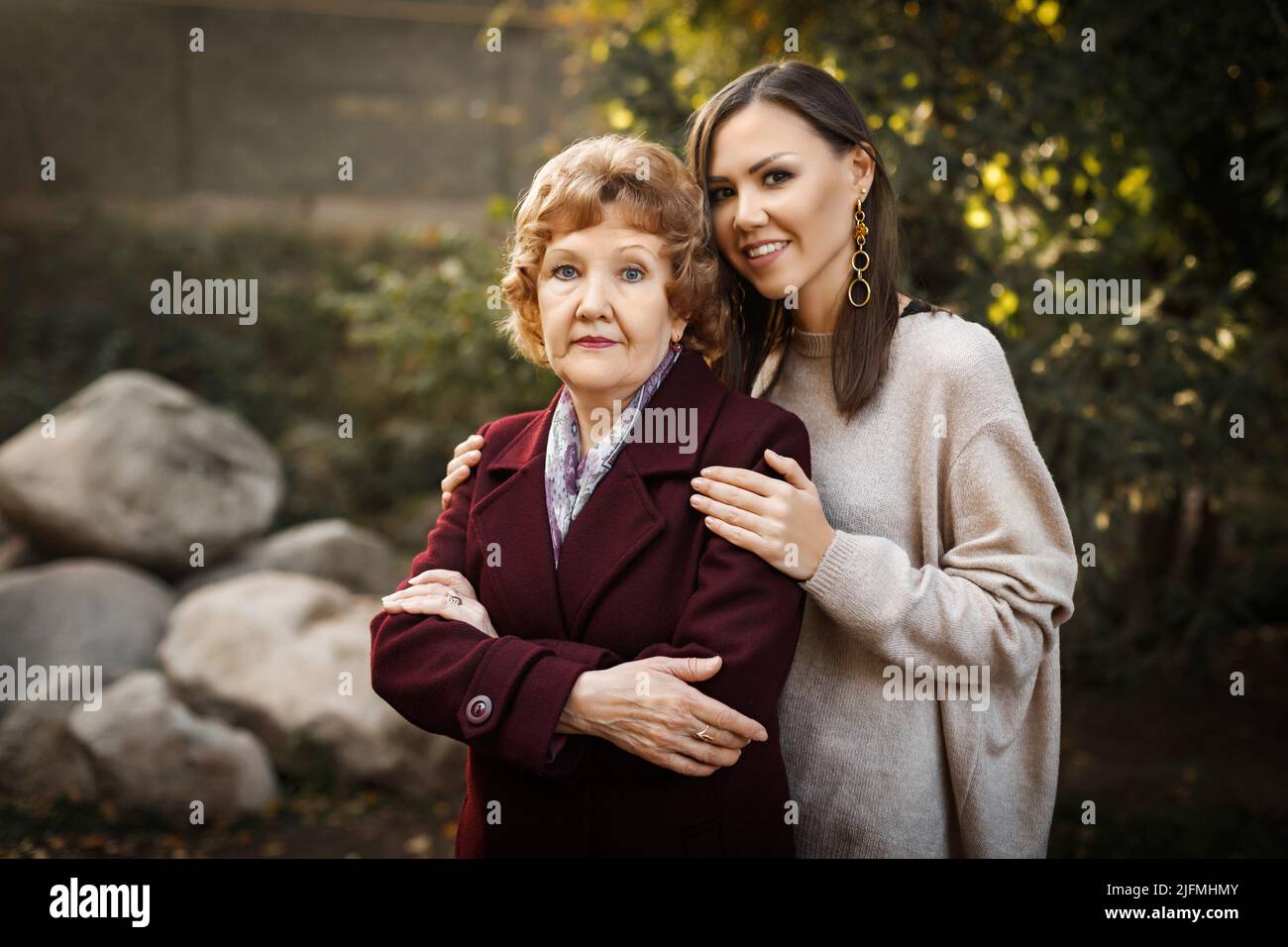 Bella figlia metis adulto abbraccia la mamma caucasica nel parco in autunno all'aperto Foto Stock