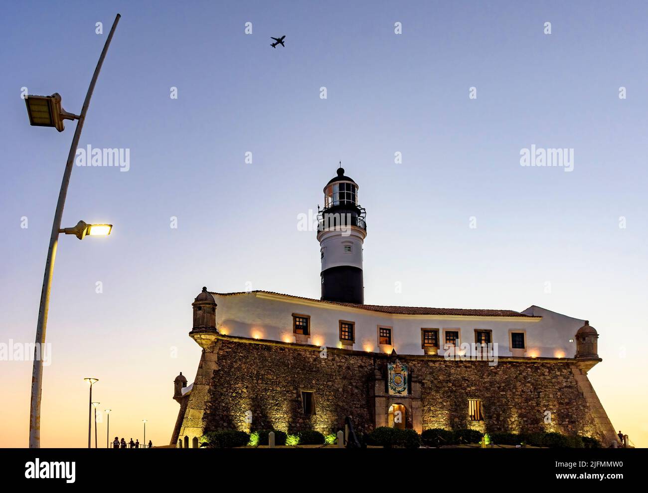 Facciata del vecchio e storico forte e faro in spiaggia barra durante il tramonto nella città di Salvador, Bahia Foto Stock