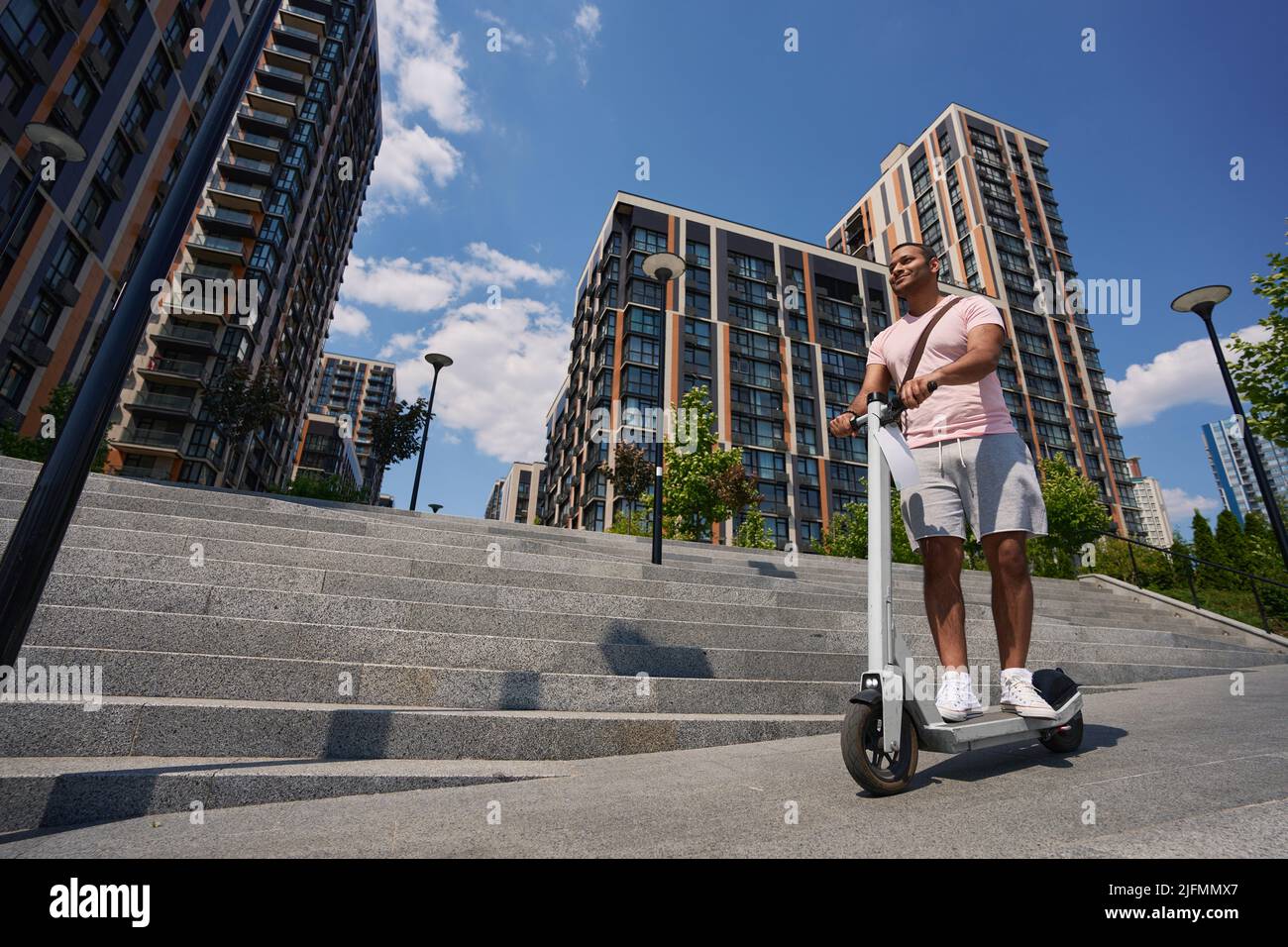 Felice giovane cittadino che guida scooter elettrico Foto Stock