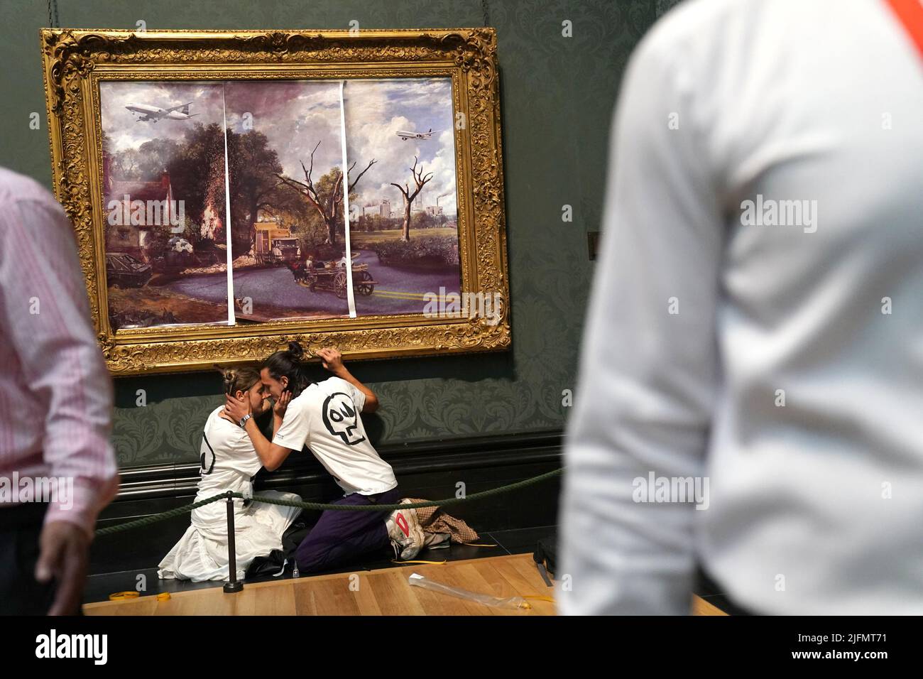 I manifestanti del gruppo di proteste sul clima Just Stop Oil, incollano le mani al telaio del The Hay Wain di John Constable dopo aver coperto per la prima volta il dipinto con la propria foto all'interno della National Gallery di Londra. Data foto: Lunedì 4 luglio 2022. Foto Stock