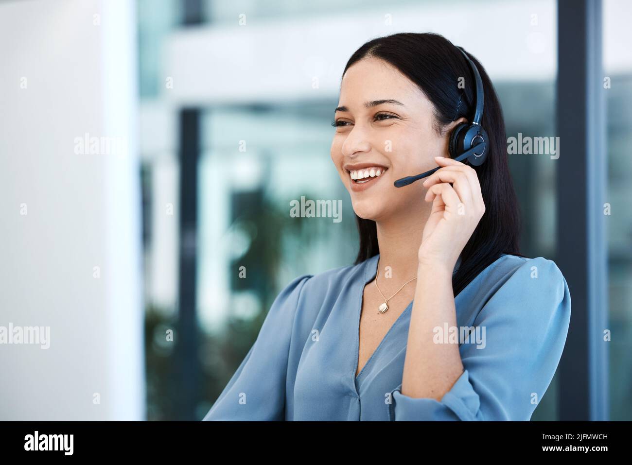 ID essere più che felice di assistere. Scatto di un giovane agente del call center che lavora su un computer in ufficio. Foto Stock