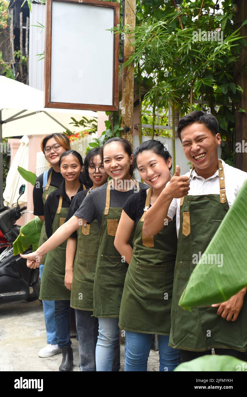 Il personale della caffetteria vietnamita sorride e si alza insieme contro un caffè Foto Stock