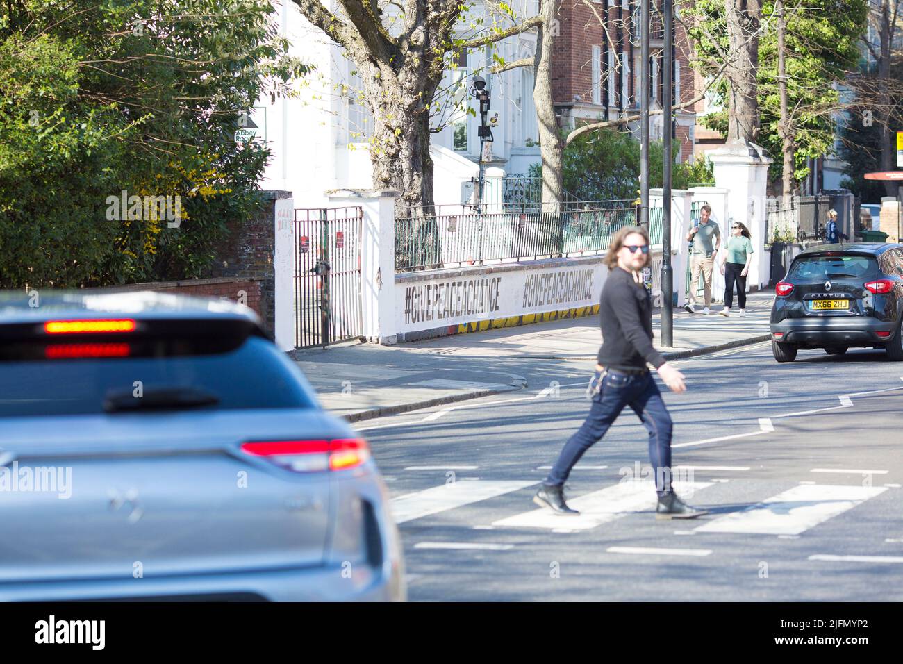 La gente si raduna intorno all'incrocio della zebra di fronte agli Abbey Road Studios di Londra. Foto Stock