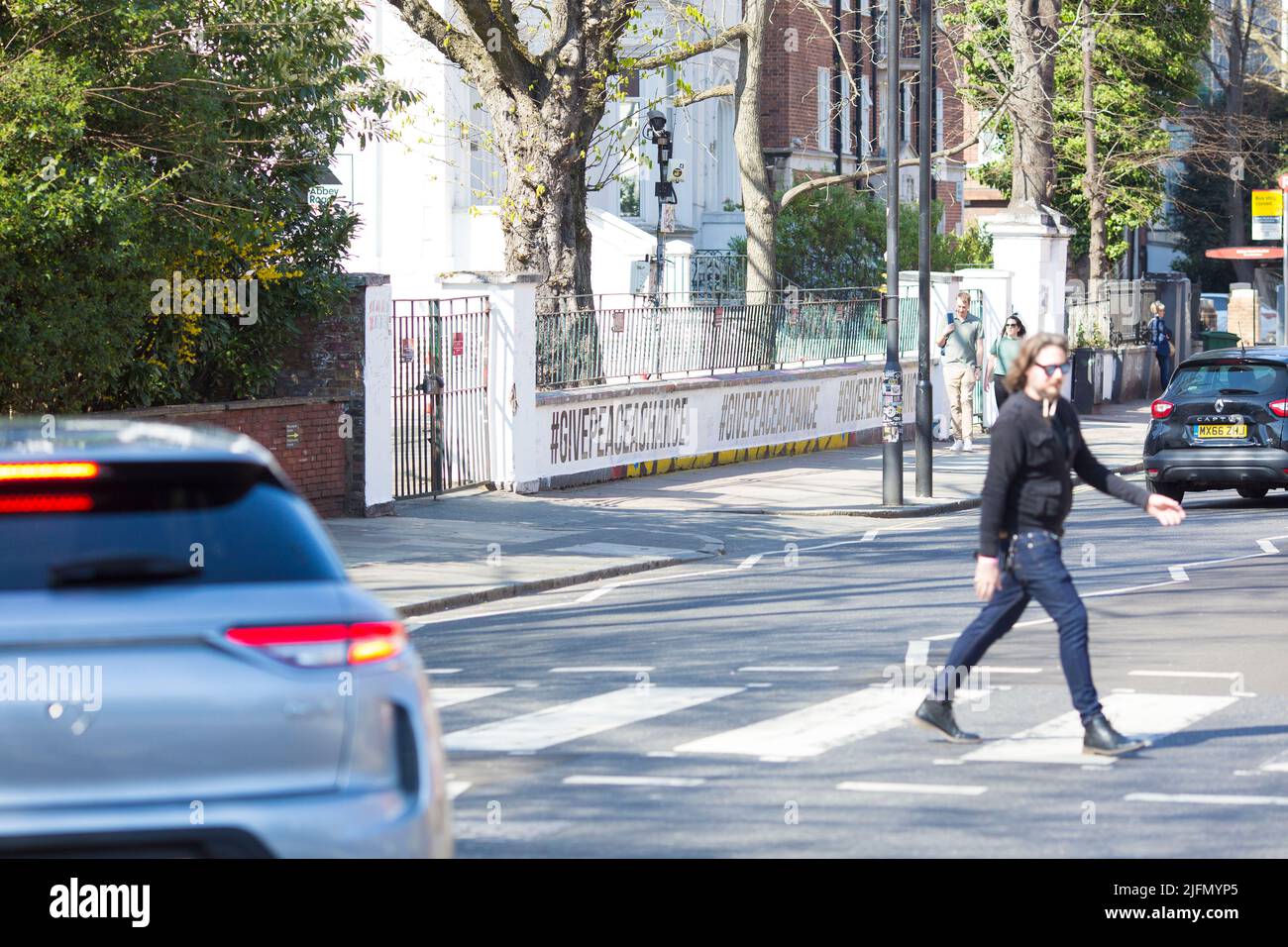 La gente si raduna intorno all'incrocio della zebra di fronte agli Abbey Road Studios di Londra. Foto Stock