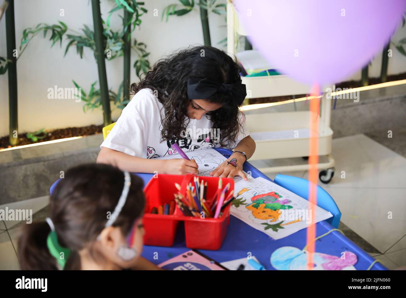 Bambina colorare su carta da colorare e divertirsi al tavolo d'arte. Un bambino che impara a colorare a casa o all'asilo. Foto Stock