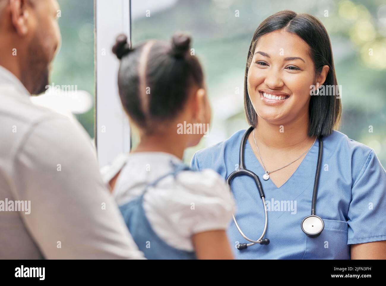 Infermiera di cura femminile che lavora con una famiglia. Infermiere cordiale che parla con la bambina paziente durante la visita in ospedale con suo padre Foto Stock