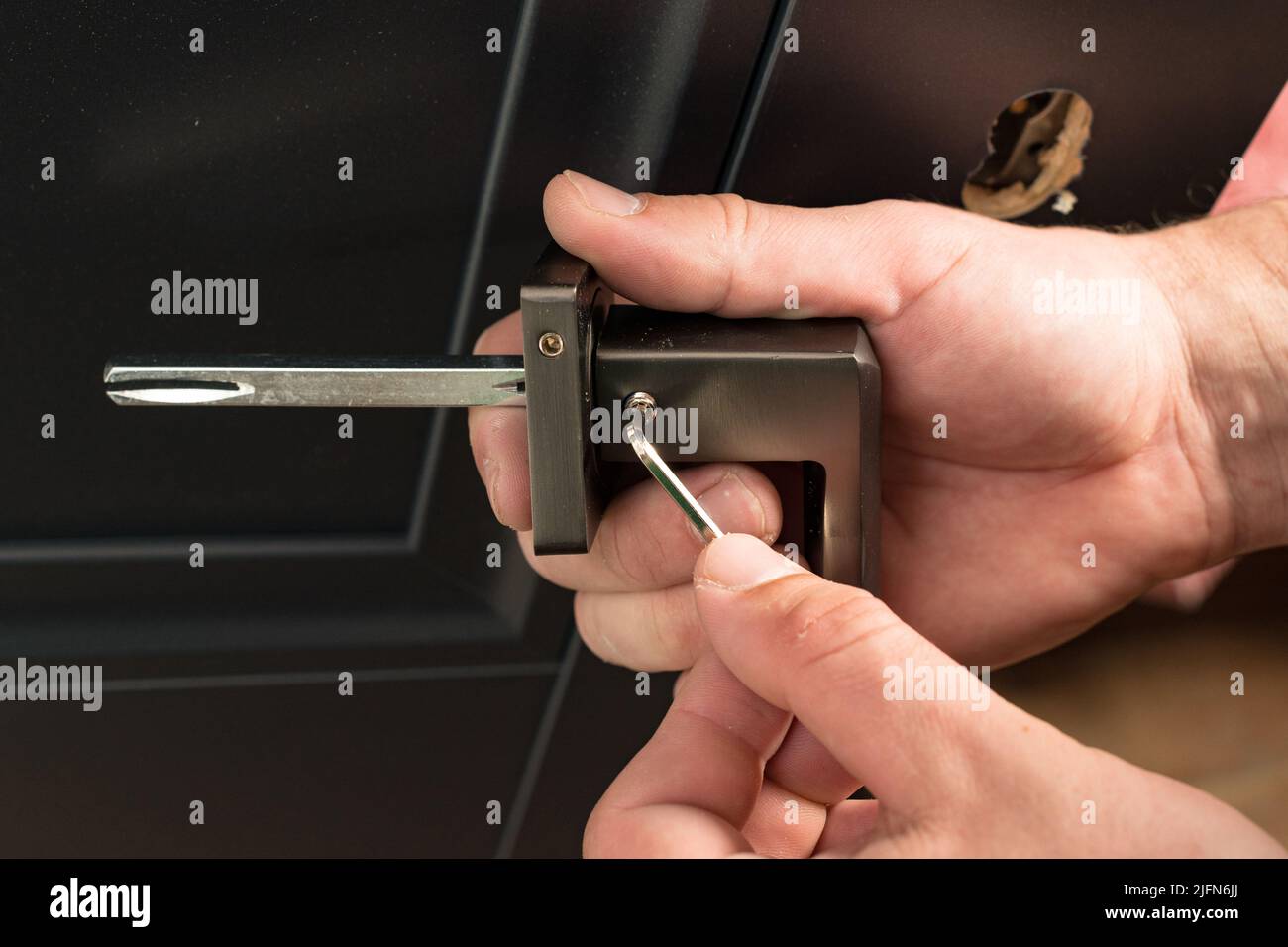 Manigmano che tiene una manopola della porta e una chiave esagonale,  montaggio della manopola della porta, pomello della porta in metallo Foto  stock - Alamy