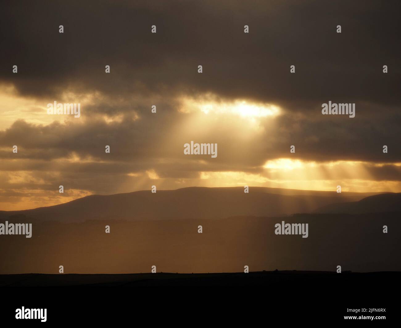 Sera raggi dorati di sole che si infrangono attraverso le rive della nuvola sul paesaggio delle colline Pennine nel North Yorkshire, Inghilterra, Regno Unito Foto Stock