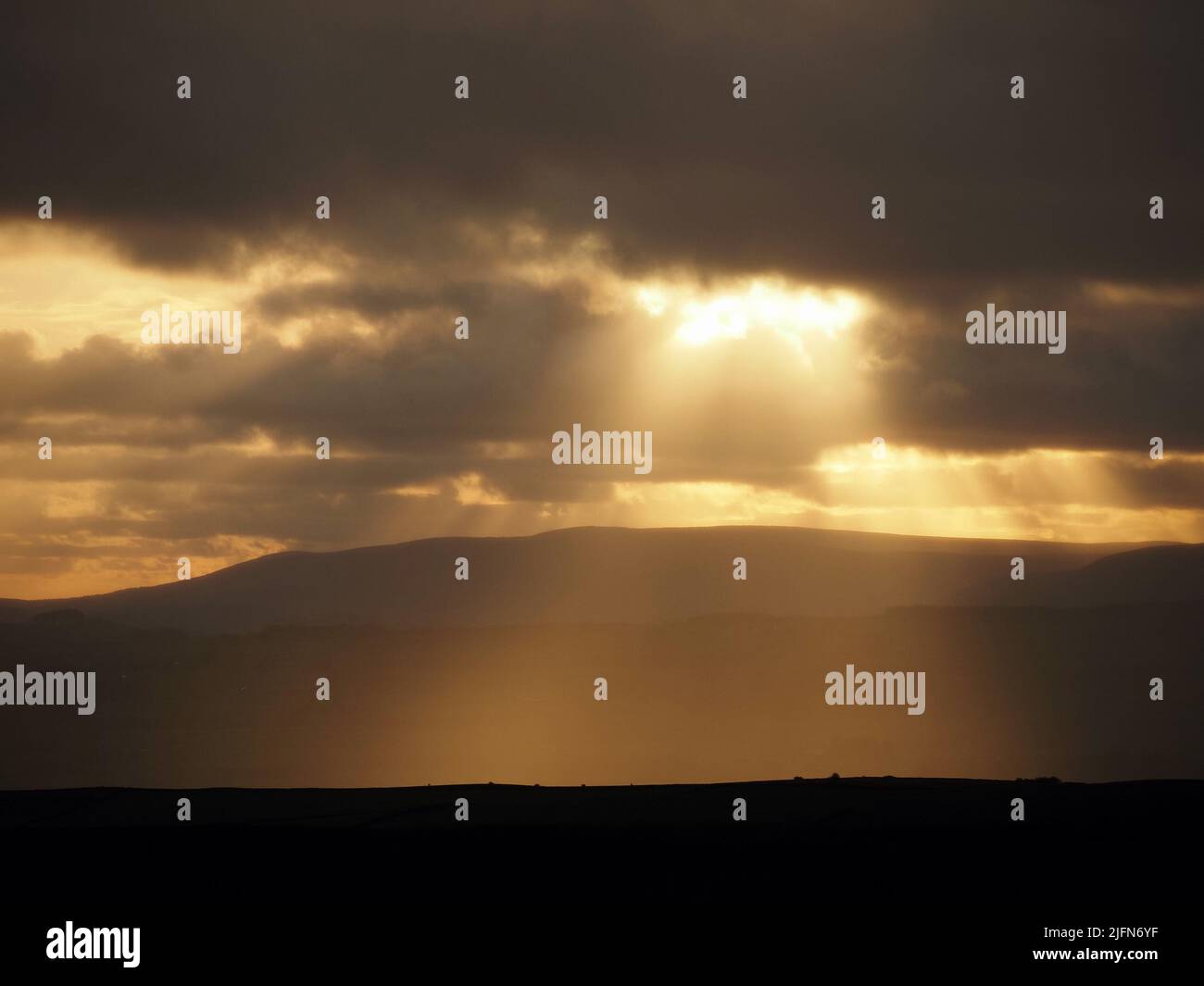 Sera raggi dorati di sole che si infrangono attraverso le rive della nuvola sul paesaggio delle colline Pennine nel North Yorkshire, Inghilterra, Regno Unito Foto Stock