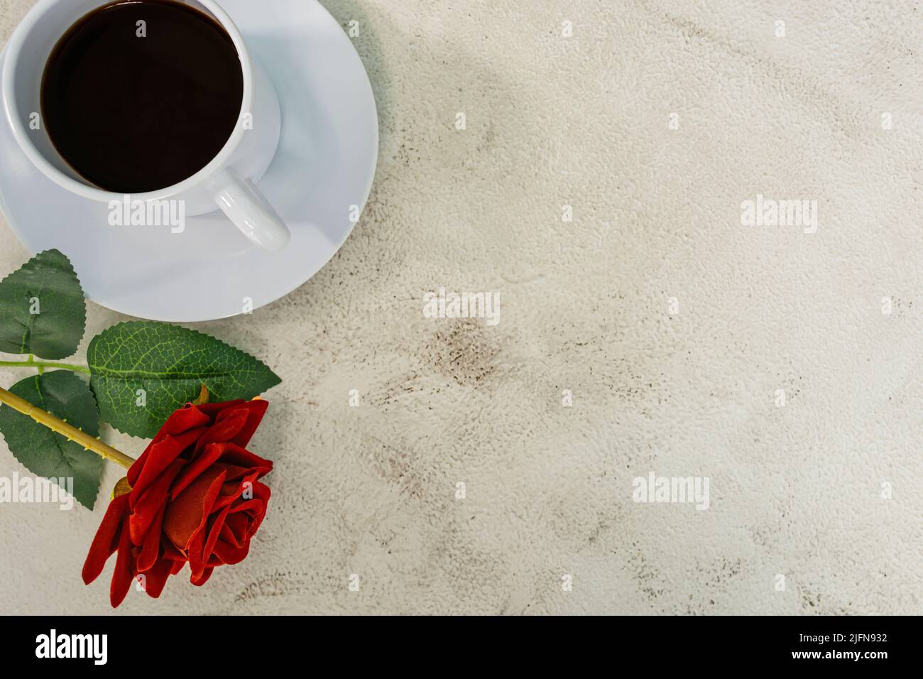 Caffè con rosa rossa sul banco in marmo. Direttamente sopra. Disposizione piatta. Spazio di copia. Foto Stock