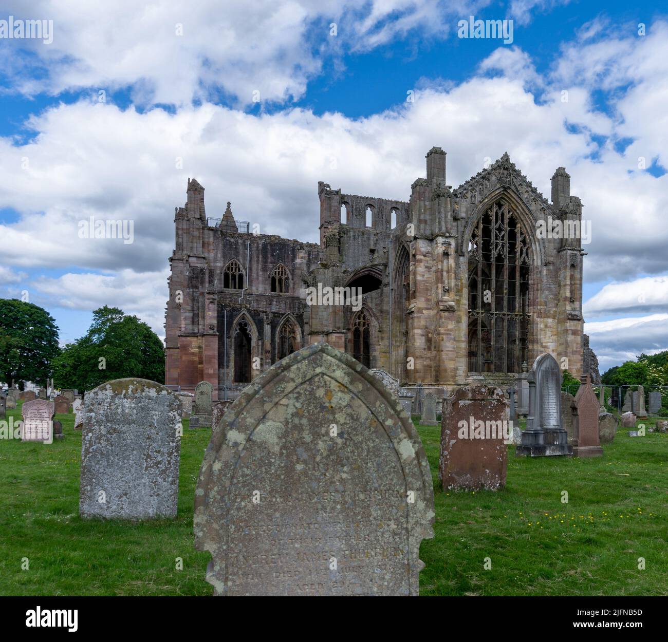 Melrose, Regno Unito - 19 Giugno, 2022: Vista delle rovine dell'abbazia di Melrose e delle pietre storiche nel cimitero della chiesa Foto Stock