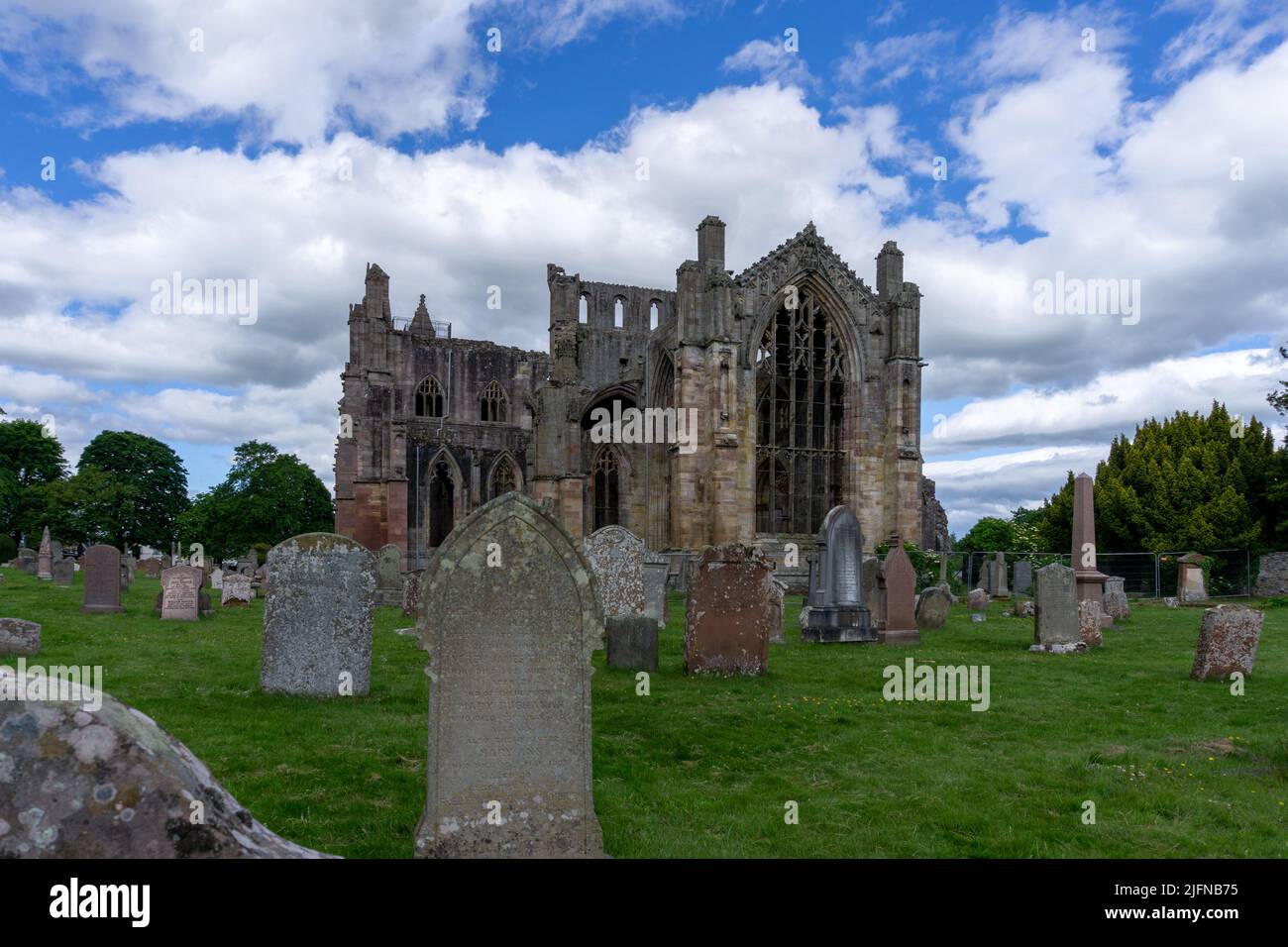 Melrose, Regno Unito - 19 Giugno, 2022: Vista delle rovine dell'abbazia di Melrose e delle pietre storiche nel cimitero della chiesa Foto Stock