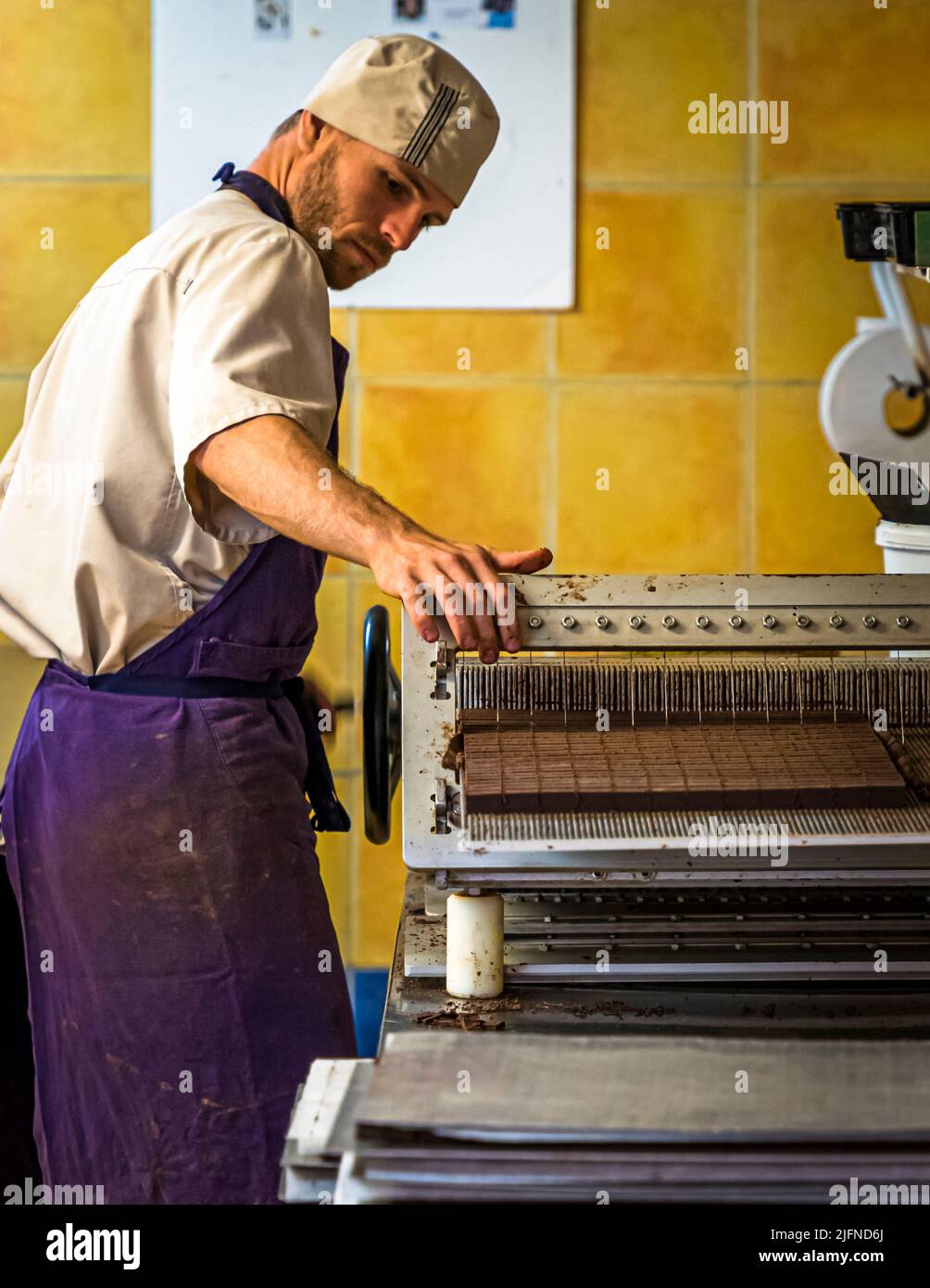 Dipendenti di Chocolaterie Frigoulette a Beaufort-sur-Gervanne (Die, Francia) taglio torrone praline. La pralina tagliata viene fornita senza un guscio di cioccolato aggiuntivo. La manifattura utilizza solo cacao in grani certificati biologici e di commercio equo e solidale di São Tomé. Foto Stock