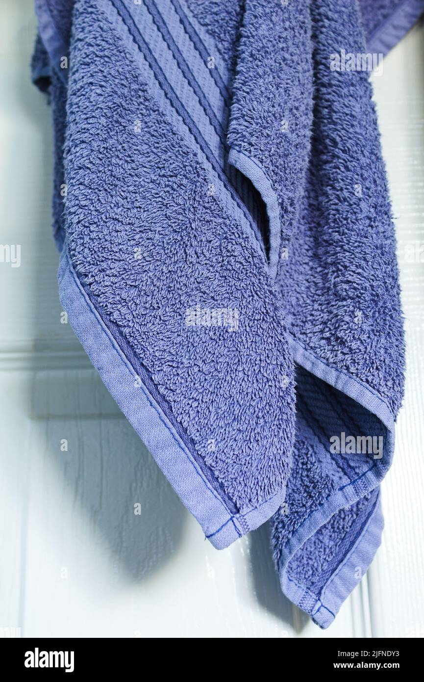asciugamano blu appeso su una porta bianca Foto Stock