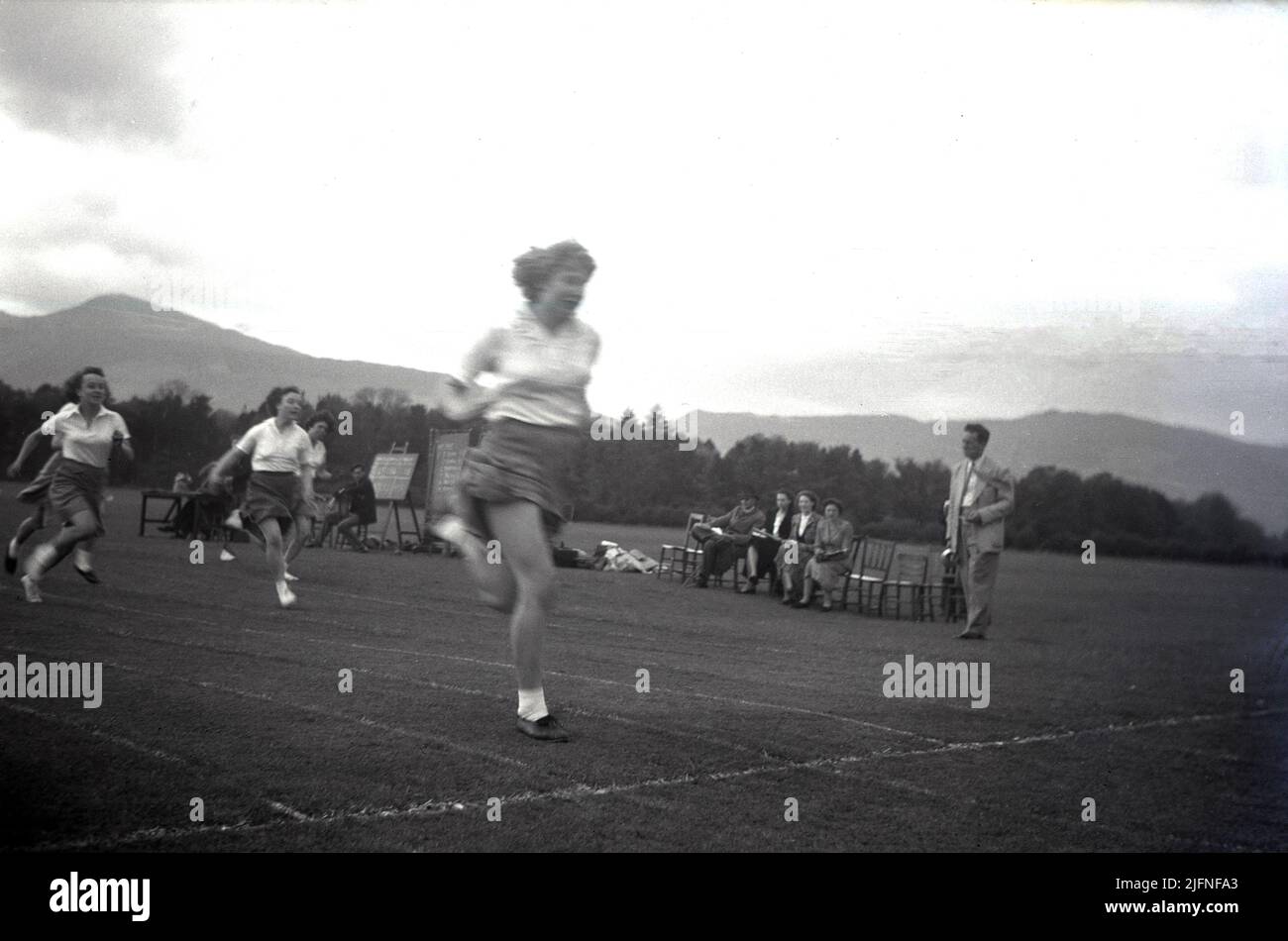 1952, storica, studentesse che competono in una corsa di sprint fuori su una pista di erba, Highlands, Scozia, Regno Unito. Foto Stock
