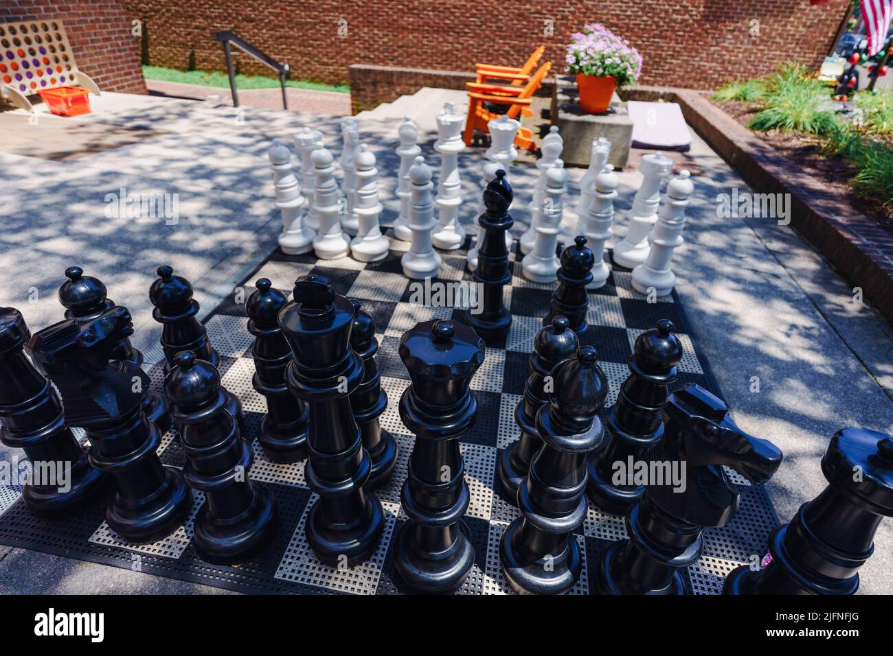 Un grande set di scacchi all'aperto attende gli sfidanti di pensiero strategico in un edificio del centro. I pezzi giganti degli scacchi si trovano in un portico su un ma Foto Stock