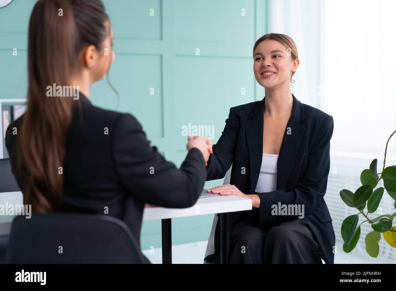 Colloquio di lavoro. Concetto di business, carriera e collocamento. Giovane donna bionda che agita la mano del candidato, mentre si siede di fronte al candidato durante il corso Foto Stock