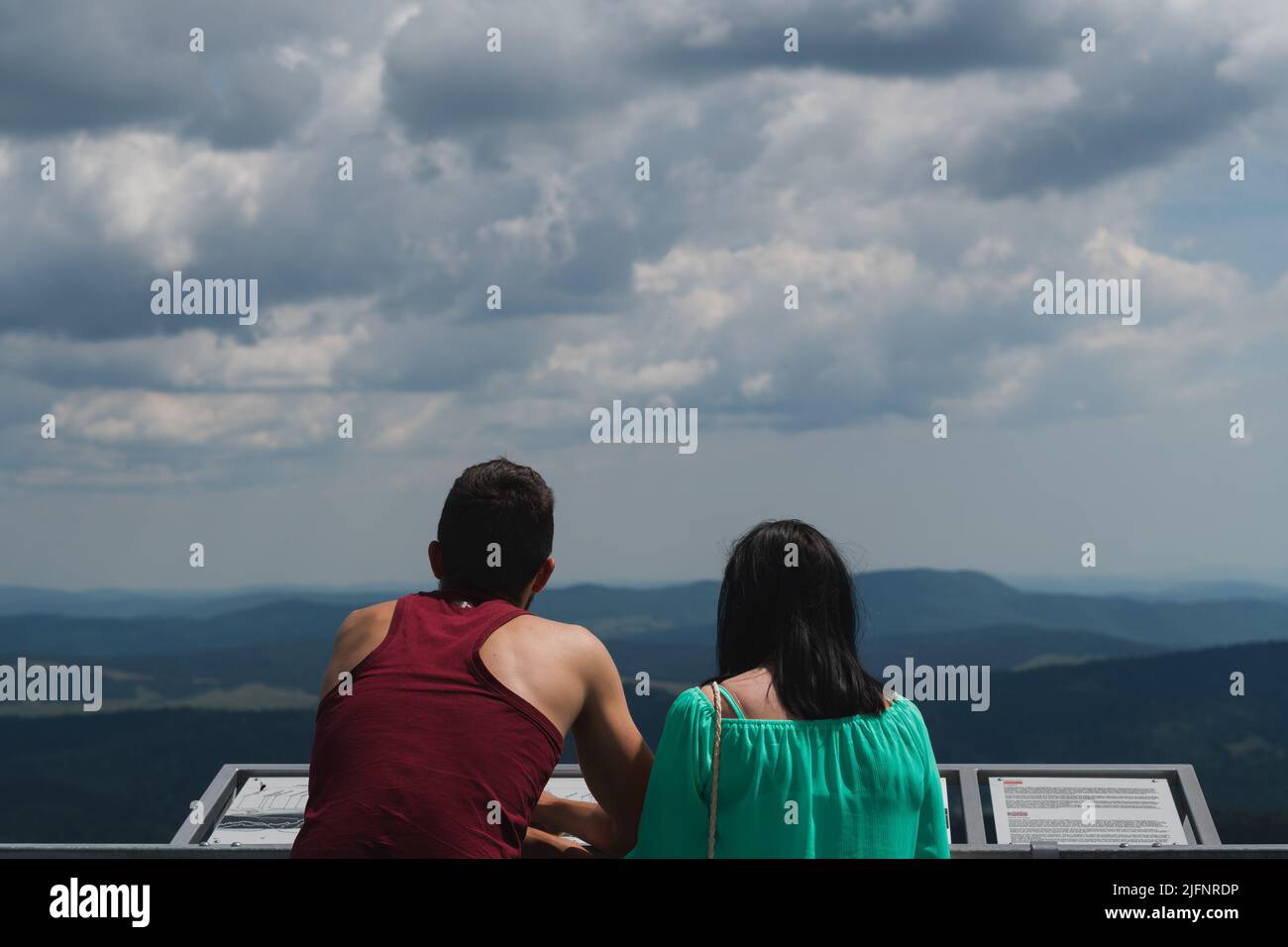 Una giovane coppia che gode di una vista sulle montagne dalla cima di una torre di avvistamento. Foto Stock