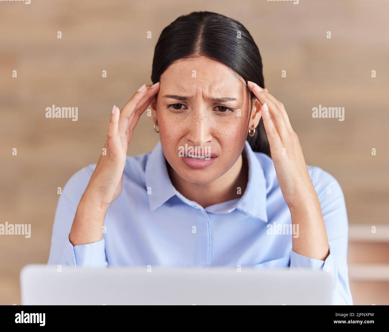 Giovane donna d'affari con gara mista che guarda stressata e stanca confusa mentre lavora su un notebook in un ufficio al lavoro. Un boss ispanico femmina in cerca Foto Stock