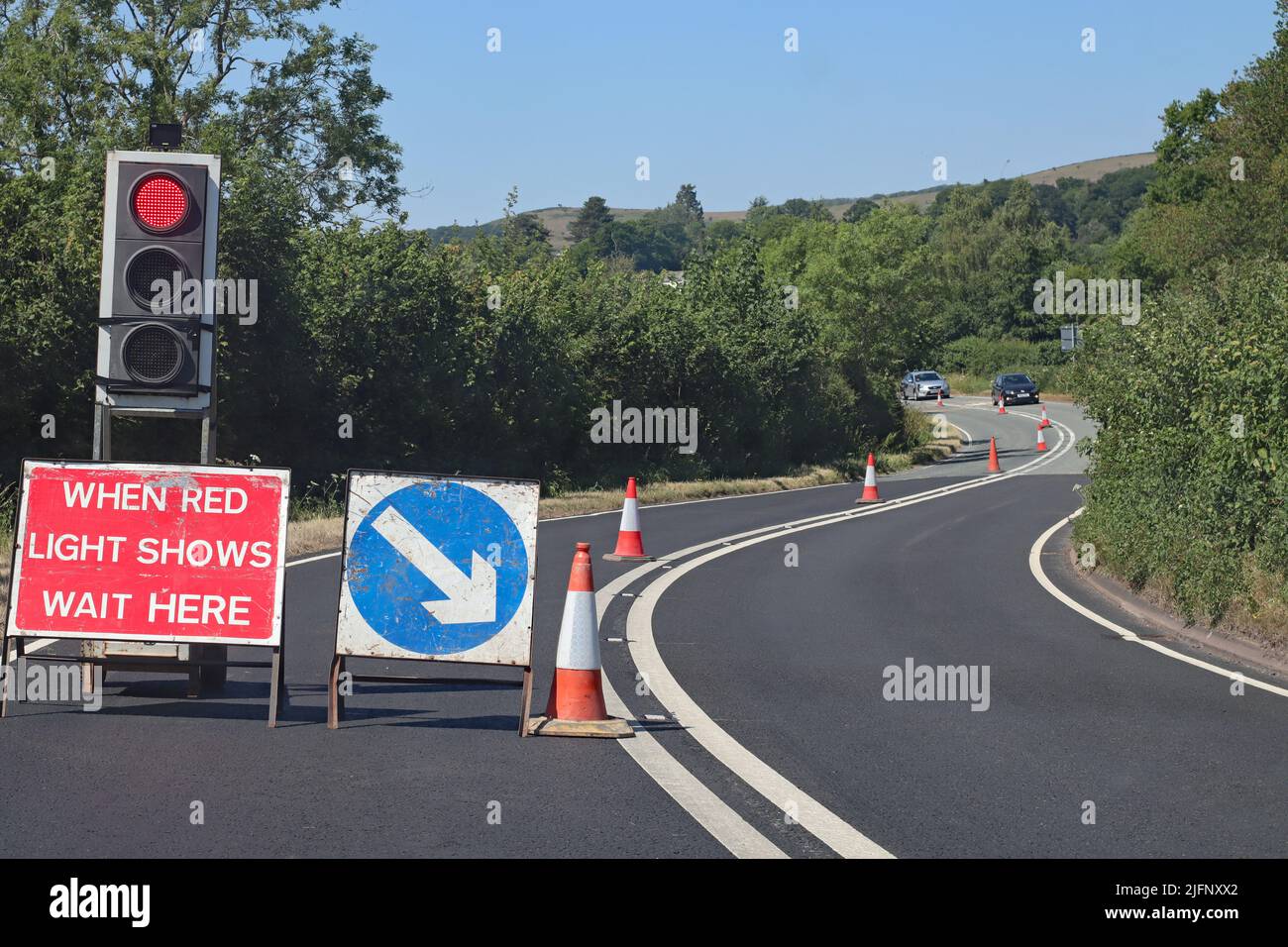 le auto si avvicinano dalla direzione opposta a lavori stradali controllati dai semafori Foto Stock