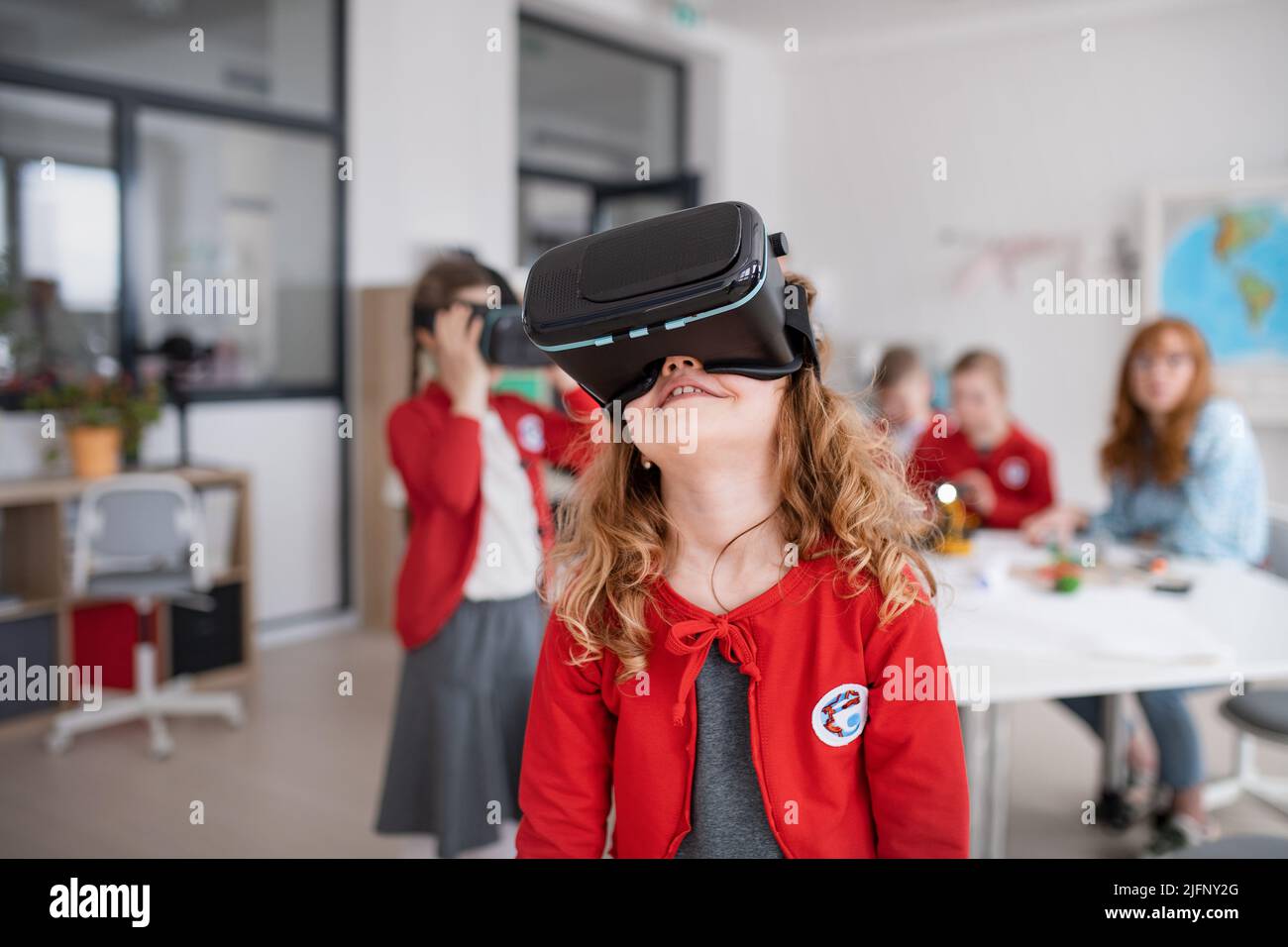 Ragazza felice che indossa occhiali di realtà virtuale a scuola in classe informatica Foto Stock