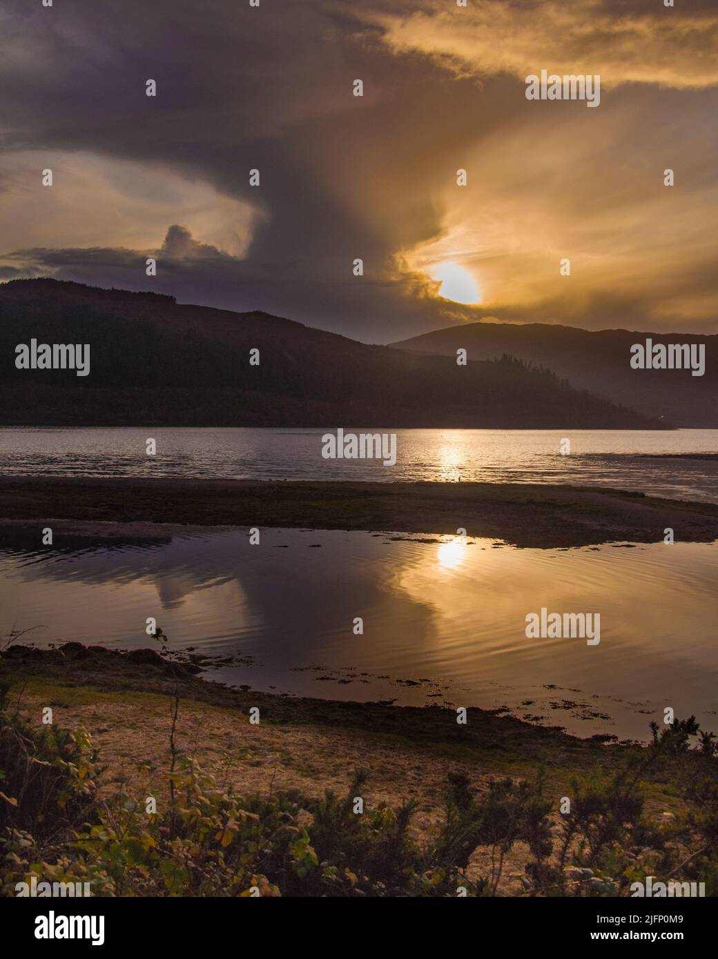 Il sole tramontato si riflette nel Loch Sunart nelle Highlands scozzesi tra le spettacolari nuvole Foto Stock