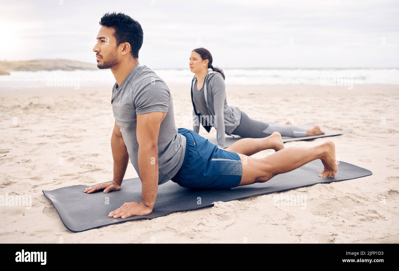 Aprire il torace mentre si allunga la schiena. Shot di una giovane coppia sportiva che fa una posa di cane rivolta verso l'alto mentre pratica lo yoga insieme sul Foto Stock