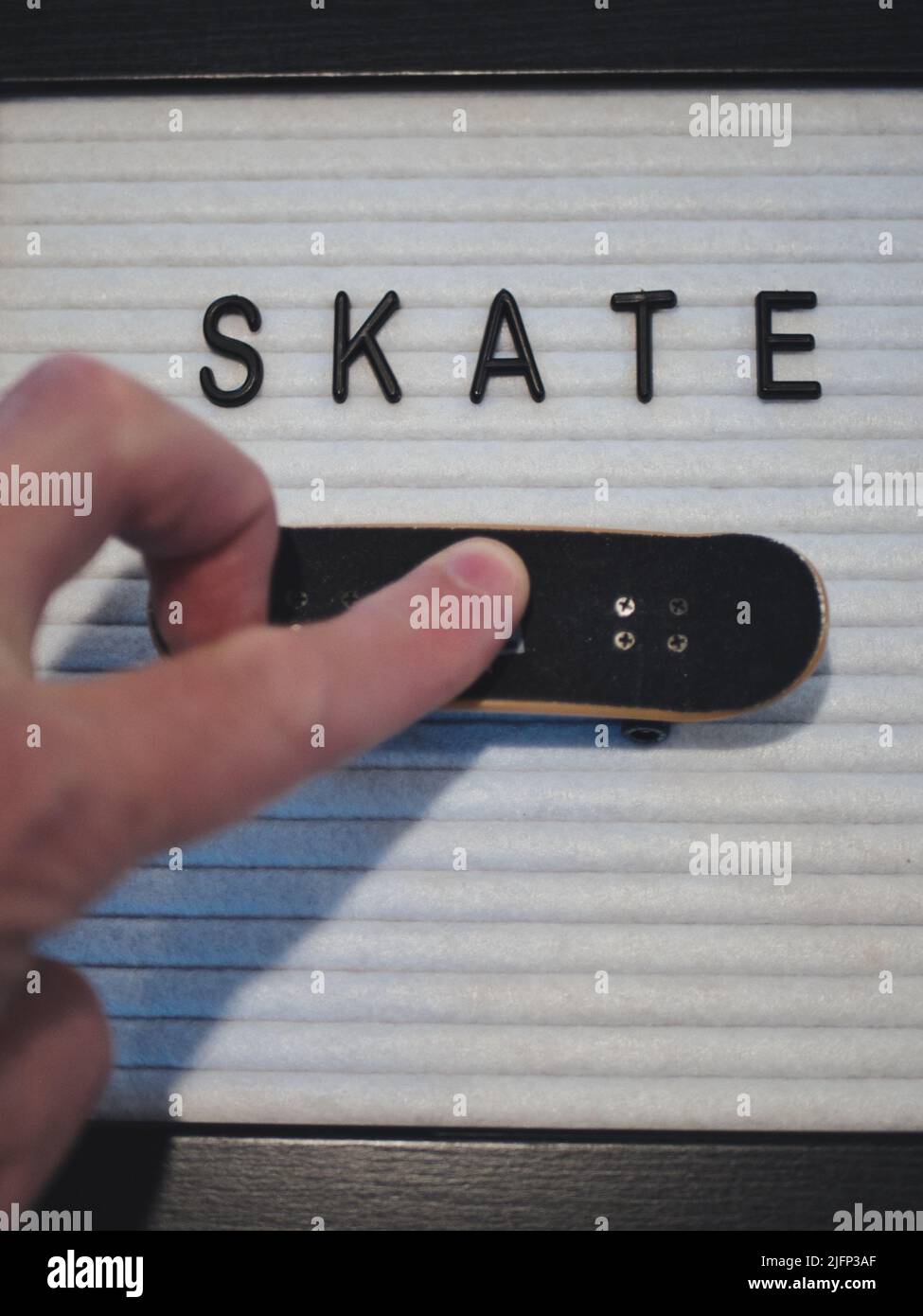 Skate in testo nero. Esperto professionale di Fingerboard che sta per fare un kickflip 360 (tre flip). Grafica divertente per illustrare lo skateboard in un royalty free Foto Stock