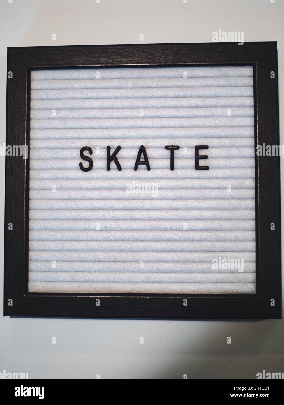 La parola Skate in plastica nera scritta su uno sfondo bianco e nero testurizzato. Foto Stock