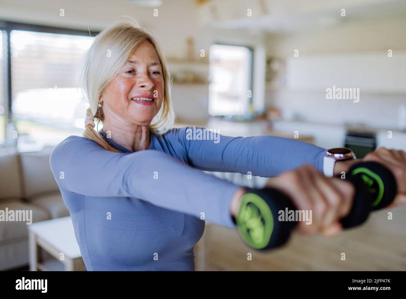 Misura la donna anziana che si esercita con i dumbbells a casa, concetto di stile di vita attivo. Foto Stock
