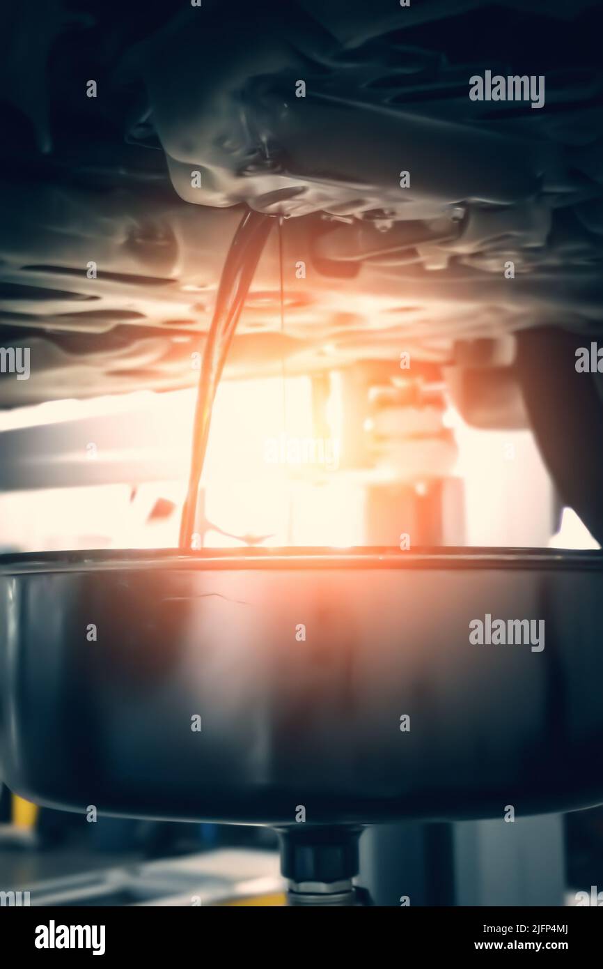 Cambio dell'olio motore. Auto in garage, processo di drenaggio vecchio olio usato scuro. Foto Stock Cambio dell'olio motore. Auto in garage, processo di drenaggio vecchio olio usato scuro. Foto Stock